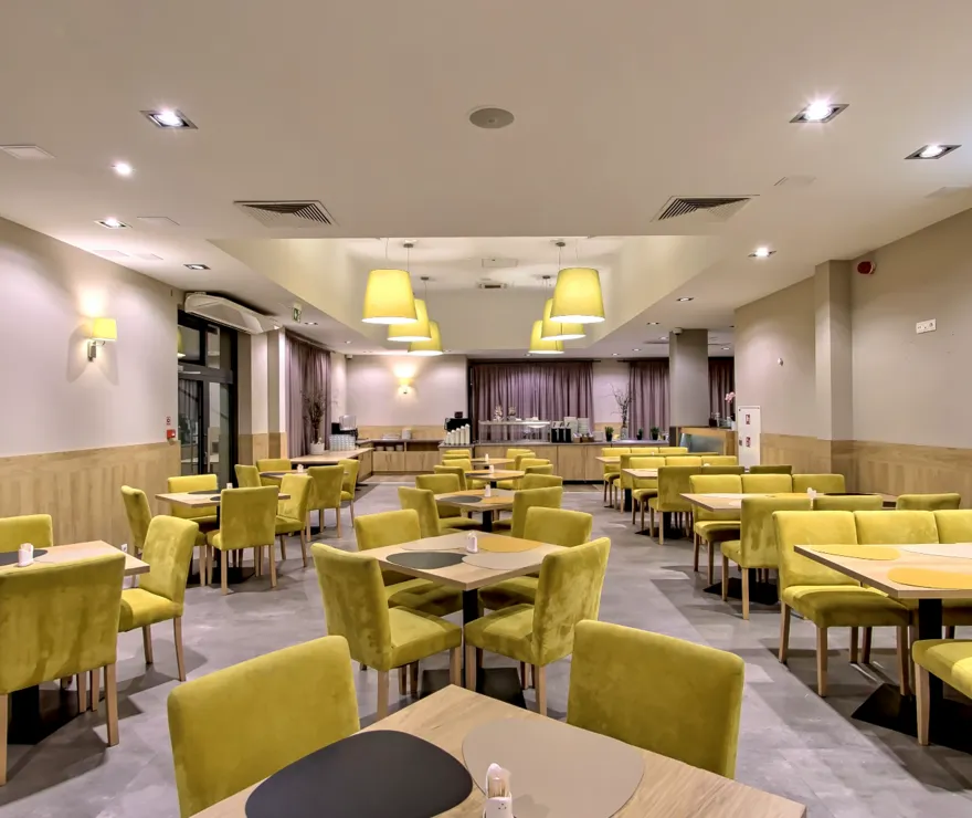 Przestronna sala restauracyjna z jasnym wnętrzem i wygodnymi miejscami siedzącymi dla gości hotelowych