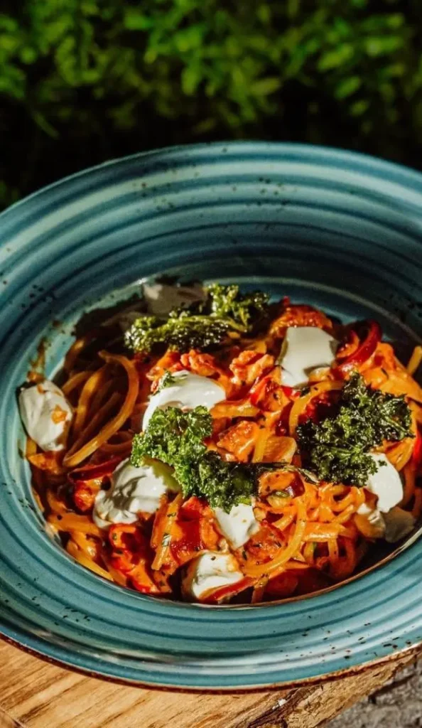 Danie w restauracji hotelowej, makaron z warzywami i serem w eleganckim podaniu