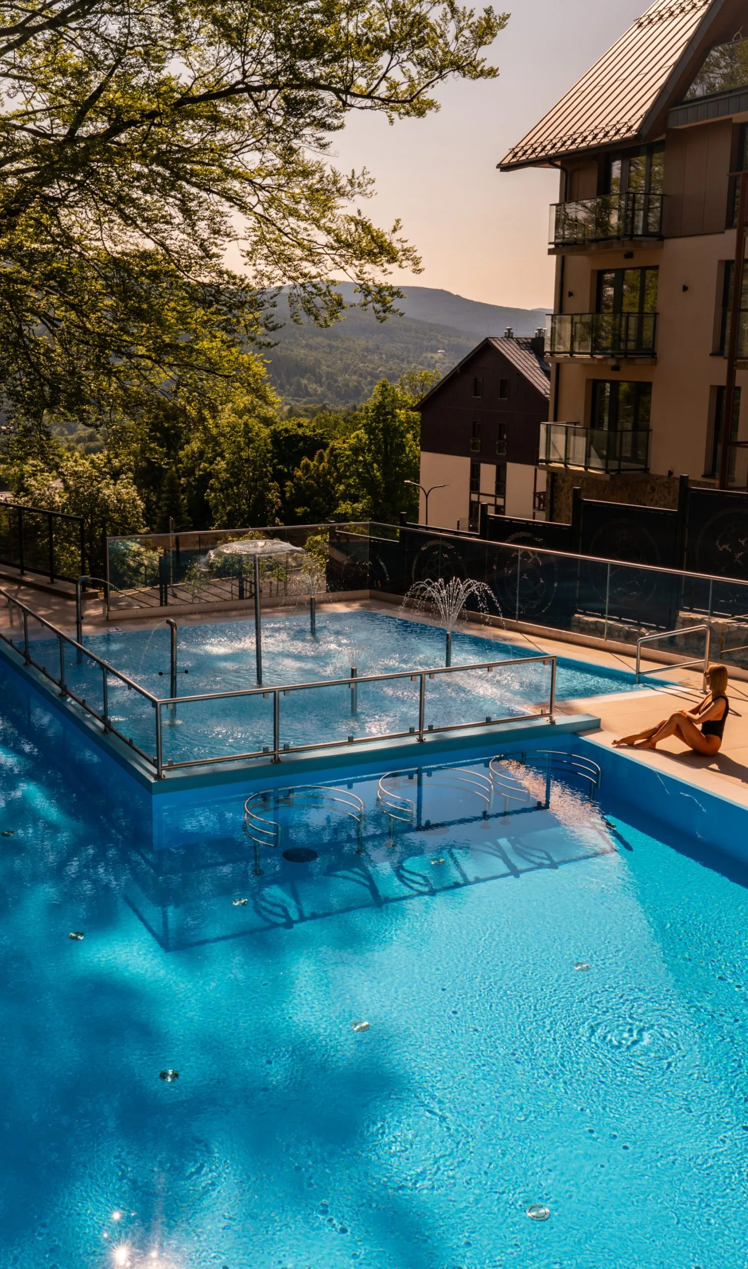 Basen hotelowy z widokiem na góry, strefa relaksu i wypoczynku na świeżym powietrzu