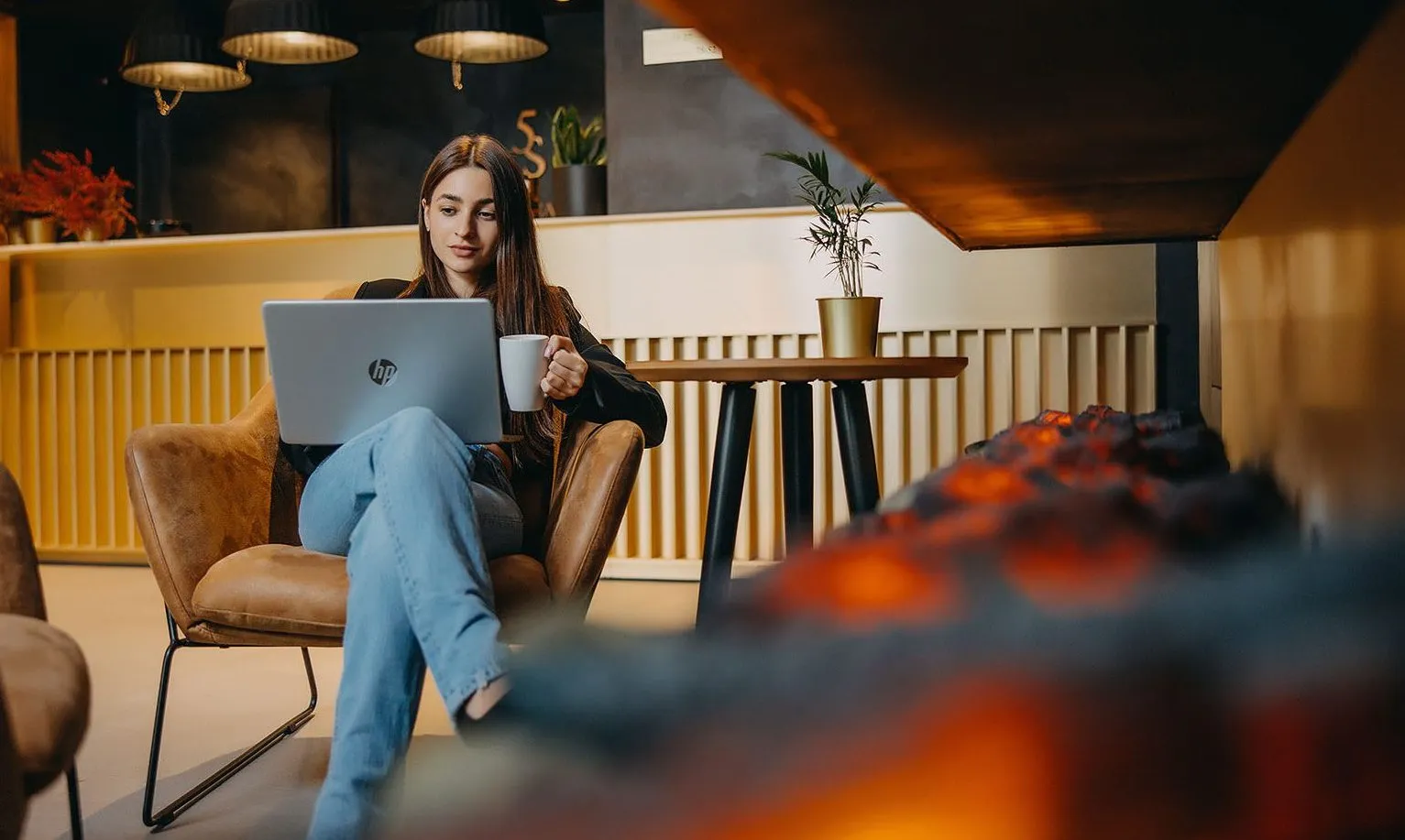 Kobieta pracująca na laptopie w hotelowej strefie lounge, komfortowa przestrzeń do pracy i odpoczynku