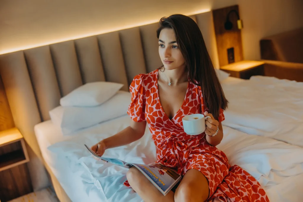 Woman relaxing in a hotel bed with a cup of coffee